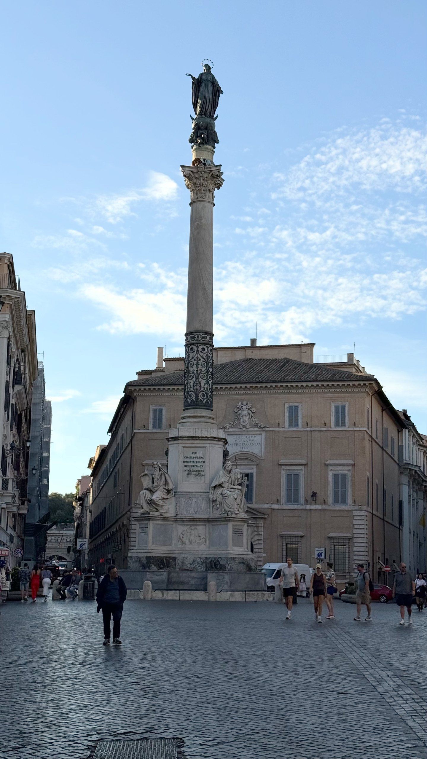 Colonna dell'Immacolata in Piazza Mignanelli, a bronze Virgin atop the tall column, a few people crossing the cobbles.