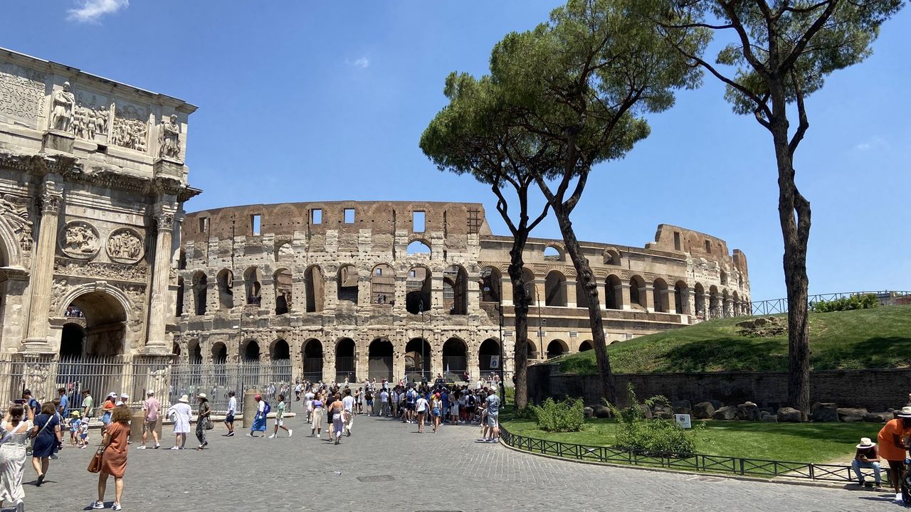 The Colosseum's exterior arches with the forecourt and scattered visitors below